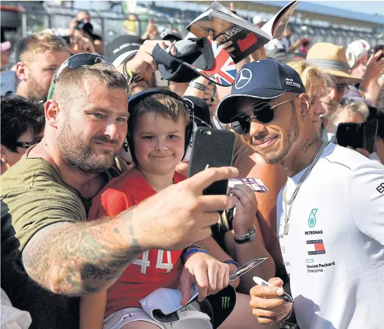  ??  ?? Mercedes driver Lewis Hamilton, right, poses for a photograph with fans at Silverston­e.