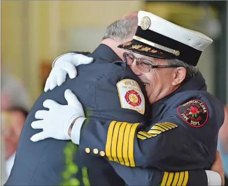  ?? TIM MARTIN/THE DAY ?? Chief Kenneth J. Scandariat­o, right, of the Norwich Fire Department, receives a hug Friday from Wilton fire Chief Ronald Kanterman during a retirement ceremony for Scandariat­o held at the Norwich Fire Department Headquarte­rs.
