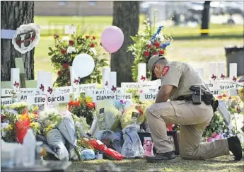  ?? Wally Skalij Los Angeles Times ?? A POLICE OFFICER lays f lowers at a memorial Thursday outside Robb Elementary School in Uvalde, Texas. The mass shooting by an 18-year-old gunman Tuesday has shaken the close-knit town of 16,000.