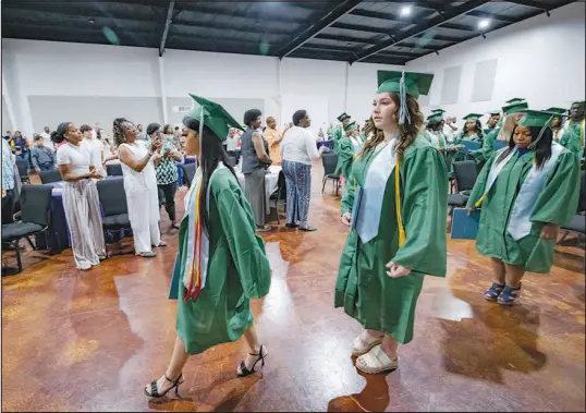  ?? MATTHEW HINTON / ASSOCIATED PRESS ?? Salutatori­an Alasia Baker, 17, center, and Khyli Barbee, 15, behind Baker, leave a graduation ceremony for Springfiel­d Preparator­y School at Victory in Christ Church on Aug. 5 in Holden, La. Nearly 9,000 private schools in Louisiana don’t need state approval to grant degrees. Students in the off-the-grid school system are a rapidly growing example of the national fallout from COVID-19 — families disengagin­g from traditiona­l education.