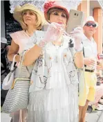  ??  ?? 2018: Art Deco clothes teamed with a mobile phone meld two very different eras, as spectators take in the vintage car parade along Emerson St, Napier at the 30th Art Deco Festival.