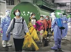  ?? Ding Ting Xinhua ?? COVID-19 PATIENTS leave a makeshift hospital in Shanghai. With millions in lockdown or held at quarantine centers, China’s economy has slowed dramatical­ly.