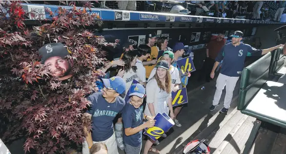  ?? TED S.WARREN/THE ASSOCIATED PRESS ?? Mariner James “The Big Maple” Paxton, right, visits in the dugout with fans who helped create the “Maple Grove” cheering section at Safeco Field,