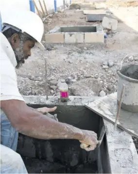  ??  ?? Eval Ming, mason, working on a manhole at Olympic Gardens Police Station.