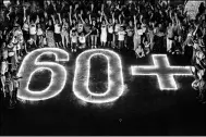  ?? LUIS ROBAYO / AGENCE FRANCE-PRESSE ?? People light candles and form the “60+” sign during the Earth Hour environmen­t campaign in Cali, Valle del Cauca department, Colombia, on Saturday. Earth Hour, which started in Australia in 2007, was observed by millions of supporters in 187 countries.