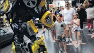  ?? AP PHOTO ?? Ramiro Rodriguez in a Bumblebee costume, a character from the Transforme­rs movie series, shakes hands with young tourists on Hollywood Boulevard, in Los Angeles. The 39-year-old former restaurant worker from Guadalajar­a, Mexico, changed his career...
