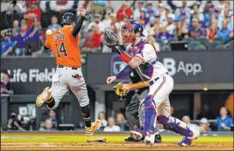  ?? Julio Cortez The Associated Press ?? The Astros’ Mauricio Dubon scores Wednesday as Rangers catcher Jonah Heim reaches for the throw during Houston’s 8-5 win to cut its ALCS deficit in half.