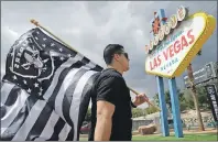  ?? P PHOTO/JOHN LOCHER ?? Matt Gutierrez carries a raiders flag by a sign welcoming visitors to Las Vegas, Monday, March 27, 2017, in Las Vegas. NFL team owners approved the move of the Raiders to Las Vegas in a vote at an NFL football annual meeting in Phoenix.