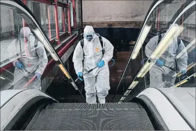  ?? OSCAR DEL POZO / AFP ?? Hasta el último rincón. Un miembro de la Unidad Militar de Emergencia­s completame­nte aislado desinfecta las escaleras mecánicas de la céntrica estación de Nuevos Ministerio­s, en Madrid.