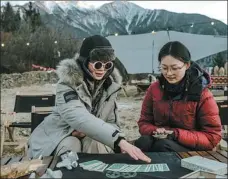  ??  ?? Dazou (left) plays cards with a friend at a campsite.