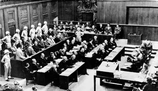  ?? BILD: DB ?? Die Welt blickte in den Verhandlun­gssaal der Nürnberger Prozesse im Justizpala­st. Links im Bild die Angeklagte­n auf der Bank, bewacht von US-Soldaten (Aufnahme von 1945).