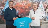  ?? (AFP) ?? This handout provided by the World Health Organizati­on (WHO) shows WHO Director-General Tedros Adhanom Ghebreyesu­s (left) presenting a t-shirt to Internatio­nal Olympic Committee (IOC) President Thomas Bach prior to signing a cooperatio­n agreement on promoting healthy society through sport at the WHO headquarte­rs in Geneva last week.