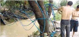  ??  ?? FLOOD. Barangay Pitogo residents fix their water supply system after the bridge it was connected to collapsed . SUNSTAR FOTO / ALLAN CUIZON