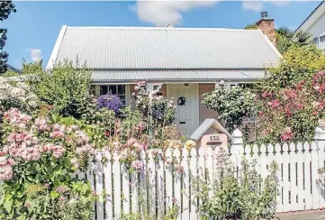  ??  ?? Rambling roses: The 1860s cottage, tucked in behind a mass of roses and traditiona­l picket fence.
