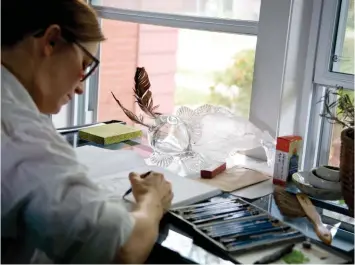  ??  ?? Meghan Sims sketches under the watchful eye of a glass-blown fish, representa­tive of another of her artistic passions.