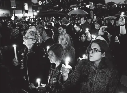  ?? MATT ROURKE/AP ?? People hold candles as they gather for a vigil in the aftermath of a deadly shooting at the Tree of Life Congregati­on.