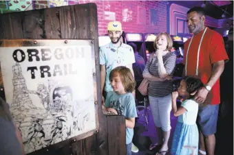  ?? Santiago Mejia / The Chronicle ?? Top: Sebastian Gross (left) plays the “Oregon Trail” arcade game as Jonathan Williams, Joanne Gross, Annleah Moore and Robert Moore watch. Left: A list of the rules of the game.