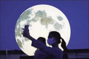  ?? Ahn Young-joon / Associated Press ?? A woman takes a selfie with a glowing full moon installati­on at a park in Seoul, South Korea, Sept. 18. The artificial full moons were installed by local officials.