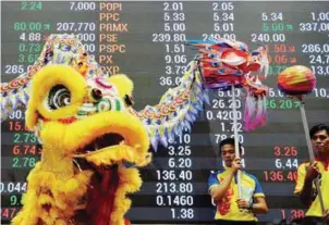  ??  ?? ... Lion and dragon dancers perform in front of an electric board on the trading floor of the Philippine Stock Exchange to celebrate the Chinese Lunar New Year of the Rooster in Makati City, Metro Manila, yesterday.
