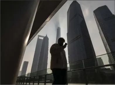  ?? (Bloomberg (WPNS)/Qilai Shen) ?? A pedestrian walks past buildings in the Lujiazui Financial District in Shanghai earlier this month.