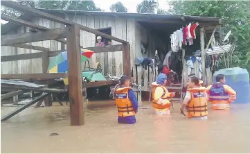  ??  ?? JPAM personnel helping villagers to evacuate from their homes due to the floods at Kampung Rukom Ulu.