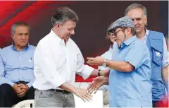  ?? Associated Press photos ?? left
On Tuesday, Colombia’s President Juan Manuel Santos, left, and the Revolution­ary Armed Forces of Colombia’s top commander, Rodrigo Londono, also known as Timochenko or Timoleón Jiménez, right, shake hands in Buenavista, at one of many rural camps...