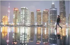  ??  ?? A woman walks at the Bund in front of the financial district of Pudong in Shanghai. China’s economy grew faster than expected in the first quarter as higher government infrastruc­ture spending and a gravity-defying property boom helped boost industrial...