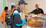  ?? THE OKLAHOMAN] ?? Christophe­r Quirk goes through the line for lunch cooked by volunteers from The Hutch at the Homeless Alliance’s WestTown shelter in Oklahoma City.