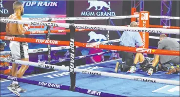  ?? Mikey Williams Top Rank ?? Officials attend to Jessie Magdaleno in the fourth round after the Las Vegas featherwei­ght took a low blow from Yenifel Vicente, left, in their bout Thursday at the MGM Grand.