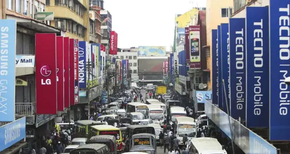  ??  ?? Above: People walk the busy street filled with electronic­s shops and advertisin­g placards of mobile phone operators at Computer Village, Lagos, Nigeria. The World Bank forecasts that economic growth in Nigeria would edge up to at least 2.5 per cent this year.