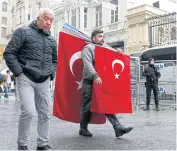  ?? EPA ?? A man carrying Turkish flags walks past a Turkish armed riot policeman in front of the Dutch consulate in Istanbul, Turkey, on Monday.