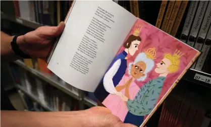  ??  ?? A bookshop employee in Törökbálin­t, Hungary, shows a page from Wonderland Is for Everyone. Photograph: Attila Kisbenedek/AFP/Getty Images