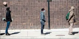  ?? ERIN HOOLEY/CHICAGO TRIBUNE ?? People waiting in line to vote in the Illinois primary March 17 practice social distancing outside their polling place.