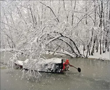  ??  ?? A woman rows her boat during heavy snowfall in the Dal Lake in Srinagar on Friday. AFP