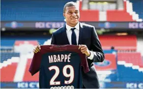  ?? — AFP ?? Welcome aboard: Paris St Germain new forward Kylian Mbappe holds his jersey during his presentati­on at the Parc des Princes Stadium yesterday.