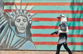  ?? AFP ?? Writing on the wall: A woman walks by a mural outside the former US embassy in Tehran.