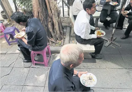  ?? PATIPAT JANTHONG ?? People from all walks of life have lunch on the streets of the capital. Despite a general economic uptick, household purchasing power remains muted.