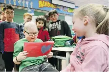  ??  ?? Left: Nine-year-old Huntre Allard reads a Valentine card from classmate Brooke Breckles after returning to Our Lady of Perpetual Help Catholic Elementary school Monday.