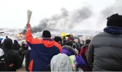  ??  ?? A fire burns in the background as opponents of the Dakota Access pipeline leave their main protest camp. (AP)