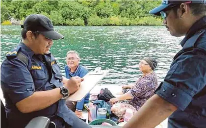  ?? [ FOTO IHSAN APMM ] ?? Anggota menyelamat­kan dua pemancing selepas bot yang dinaiki karam, di Perairan Pulau Nusa, Kunak.