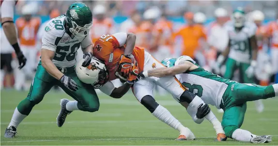  ?? DARRYL DYCK/The Canadian Press ?? B.C. Lions’ Cameron Morrah, centre, is tackled by Saskatchew­an Roughrider­s’ Jake Doughty, left, and Macho Harris during the first half of their game in Vancouver on Friday.