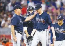  ?? THE ASSOCIATED PRESS ?? Braves manager Brian Snitker, left, relieves starting pitcher Max Fried during the fifth inning of Sunday’s game against the Marlins in Miami.