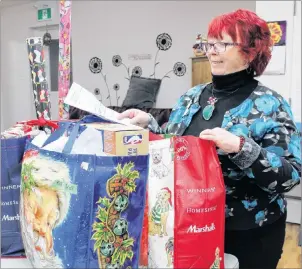  ?? NANCY KING/CAPE BRETON POST ?? Wanda Earhart of Every Woman’s Centre looks over some of the packages that have already been dropped off in support of the centre’s annual Adopt a Family program. Each year the program helps more than 600 families have a merrier Christmas season. To adopt a family, contact the centre.