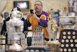  ?? — THE ASSOCIATED PRESS ?? A fan takes pictures of NHL award trophies on display at the MGM Grand Tuesday in Las Vegas. The league is set to approve rule changes Wednesday for the upcoming season.