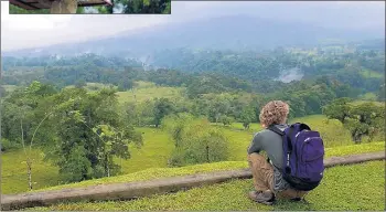  ??  ?? An American tourist tries to get a glimpse of the cloud-covered Arenal Volcano rising above the tropical forest near La Fortuna, Costa Rica.