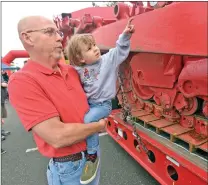  ?? Dan Watson/The Signal ?? Richard Morris holds up Ian Morris, 2, to get a closeup look at a Los Angeles County Fire Department bulldozer.