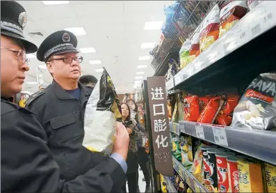  ?? LIU HANG / FOR CHINA DAILY ?? Officers from the Beijing Food and Drug Administra­tion check imported food at a supermarke­t on Thursday.