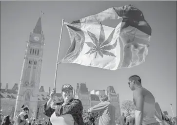  ?? Chris Roussakis AFP/Getty Images ?? A WOMAN waves a flag with a pot leaf on it to celebrate National Marijuana Day in Ottawa, Canada, in April 2016. In two months, Canada will become the first G-7 country to legalize the recreation­al use of marijuana.
