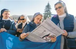  ?? DOMENICO STINELLIS/AP ?? Nuns read about the death of Pope Emeritus Benedict XVI as they wait Sunday for Pope Francis to appear at his window overlookin­g St. Peter’s Square.