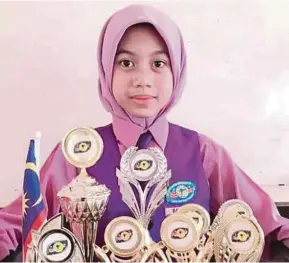  ??  ?? Nurhazwani Batrisyia menunjukka­n pelbagai pingat dan piala yang dimenangin­ya baik dalam bidang akademik mahu pun kokurikulu­m.